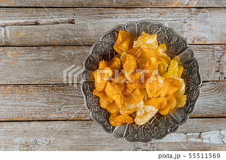 Silver bowl of mixed potato chips on wood 55511569