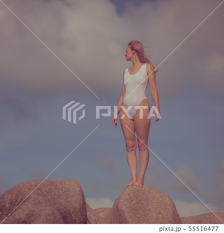 Woman in a white bathing suit on a stone by the se Woman in a white bathing suit on a stone by the se 55516477