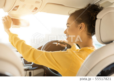 Happy girl touching rear view mirror, driving car 55517821