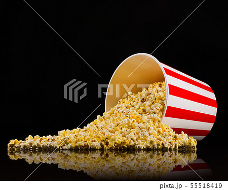 Scattered popcorn from paper striped bucket isolated on black background 55518419
