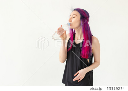 Young girl hipster with colored hair drinks water from a bottle after intense physical training in Young girl hipster with colored hair drinks water from a bottle after intense physical training in 55519274