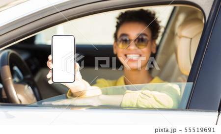 Happy afro woman in auto showing smartphone with blank screen 55519691