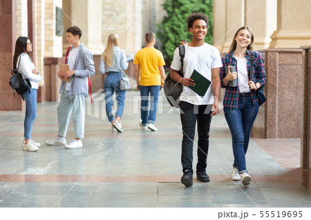 Happy college classmates walking in campus during break 55519695