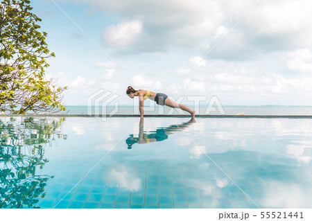 Woman relaxing in yoga over the pool on beach 55521441