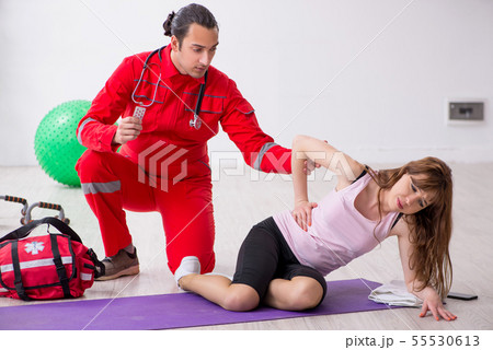Paramedic in red visiting young woman in gym 55530613