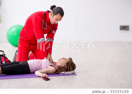 Paramedic in red visiting young woman in gym 55535150