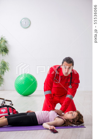 Paramedic in red visiting young woman in gym 55536066