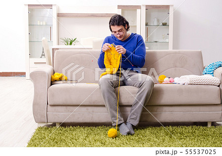 Young good looking man knitting at home Young good looking man knitting at home 55537025