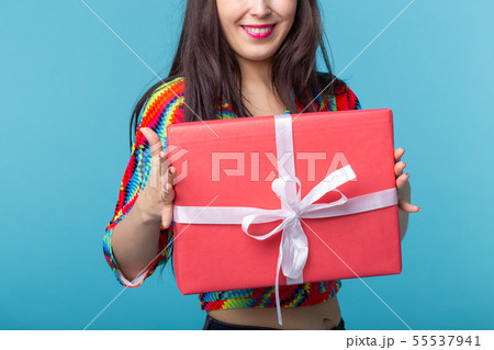 Close-up pf beautiful young brunette girl holding a red gift box in her hands while standing against Close-up pf beautiful young brunette girl holding a red gift box in her hands while standing against 55537941