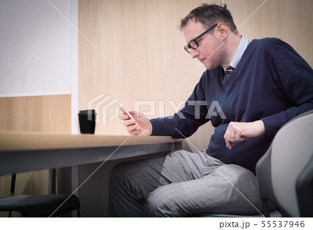 A man looking at his phone while killing time A man looking at his phone while killing time 55537946