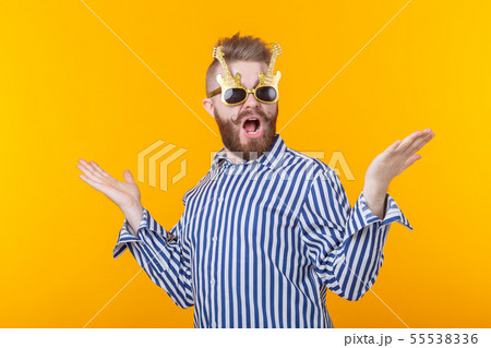Positive young man with glasses in the form of guitars rejoices having lifted his hands up against a 55538336