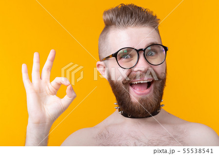 Positive funny hipster shirtless guy with a rocker collar shows ok on a yellow background. Concept Positive funny hipster shirtless guy with a rocker collar shows ok on a yellow background. Concept 55538541