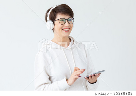 Beautiful woman 40-50 years old listening music in big headphone and holding tablet on white 55539305