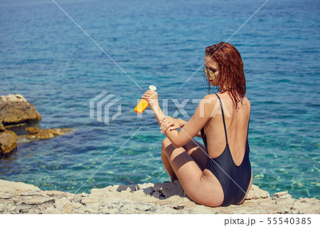 sexy young woman on the beach applying sun cream 55540385