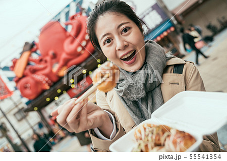 tourist smiling and showing tasty octopus balls 55541354