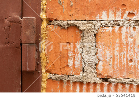 A close up of an old red brick wall and a band of a brown painted metal garage door 55541419