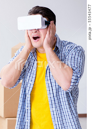 Young man wearing VR glasses moving in new apartment Young man wearing VR glasses moving in new apartment 55543477