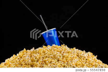 Blue cup with tube installed on scattered popcorn isolated on black background Blue cup with tube installed on scattered popcorn isolated on black background 55547850