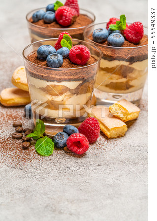 Classic tiramisu dessert with blueberries and raspberries and savoiardi cookies in a glass on Classic tiramisu dessert with blueberries and raspberries and savoiardi cookies in a glass on 55549337