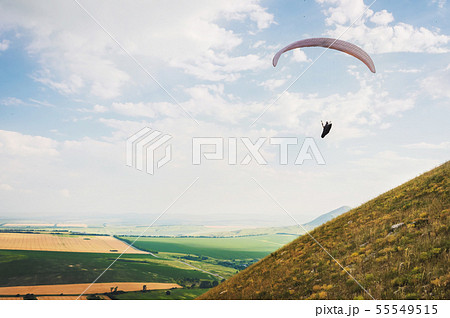 A paraglider flies in the sky in a cocoon suit on a paraglider over the Caucasian countryside with 55549515