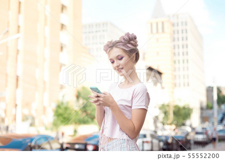 Portrait of a young stylish hipster woman walking down the street dressed in a trendy outfit, a pink 55552200