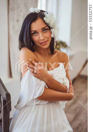 sexy brunette in white dress sitting by the window 55552757
