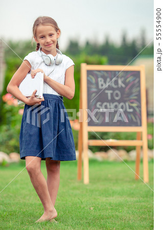 Happy little schoolgirl with a chalkboard outdoor Happy little schoolgirl with a chalkboard outdoor 55554900