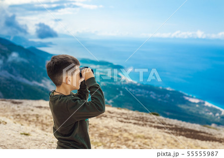 Young boy at mountain top looking through binoculars Young boy at mountain top looking through binoculars 55555987
