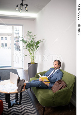 Businessman putting legs on table reading book having little break 55557035