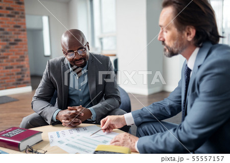 Dark-skinned man speaking with his lawyer sitting in the office 55557157
