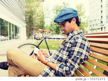 man with notebook or diary writing on city street 55572371