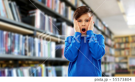 terrified boy over book shelves at library 55573804