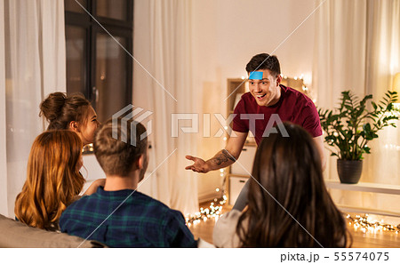 friends playing guessing game at home in evening 55574075