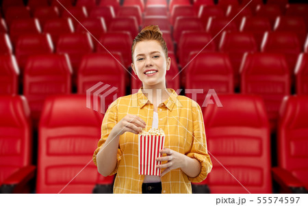 redhead teenage girl with popcorn at movie theater redhead teenage girl with popcorn at movie theater 55574597