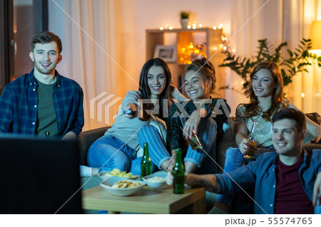 Friends With Drinks And Snacks Watching Tv At Homeの写真素材