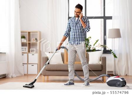 man with vacuum cleaner calling on cell at home 55574796
