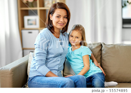 mother and daughter sitting on sofa at home 55574895