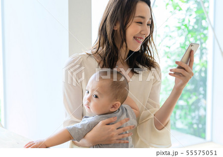 子供を抱きながらスマホを見る女性 子供を抱きながらスマホを見る女性 55575051
