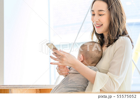 子供を抱きながらスマホを見る女性 55575052