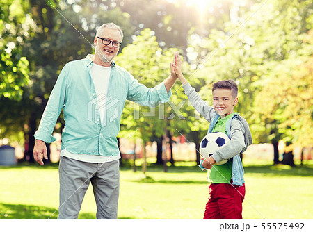 old man and boy with soccer ball making high five 55575492