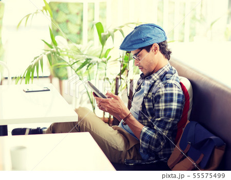 man with tablet pc sitting at cafe table 55575499