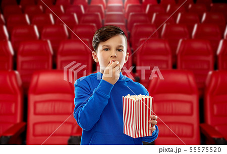 boy in blue hoodie eating popcorn at movie theater boy in blue hoodie eating popcorn at movie theater 55575520