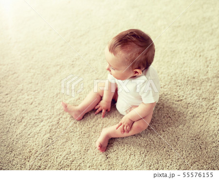 happy baby boy or girl sitting on floor at home 55576155