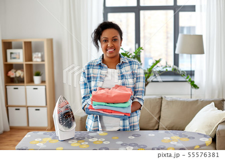 african american woman with ironed clothes at home african american woman with ironed clothes at home 55576381