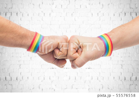hands with gay pride wristbands make fist bump 55576558