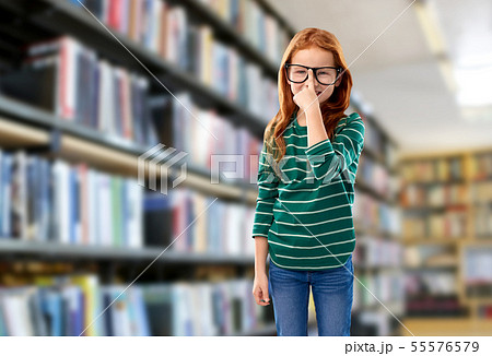 cute red haired student girl in glasses at library 55576579