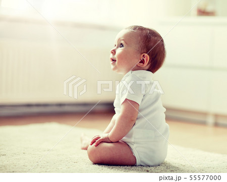 happy baby boy or girl sitting on floor at home 55577000