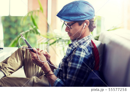 man with tablet pc and earphones sitting at cafe 55577258