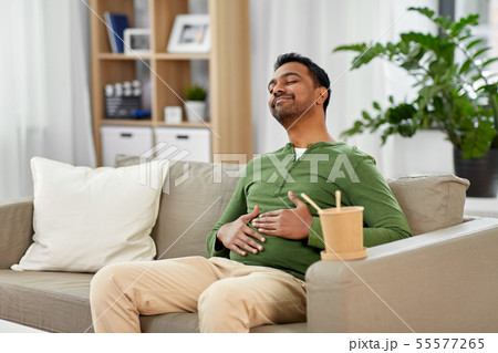pleased indian man eating takeaway food at home pleased indian man eating takeaway food at home 55577265