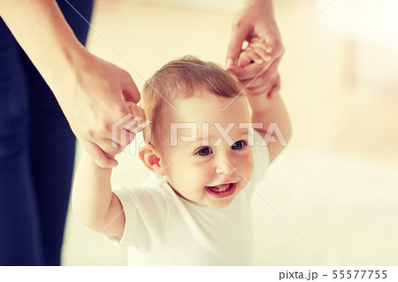 happy baby learning to walk with mother help 55577755